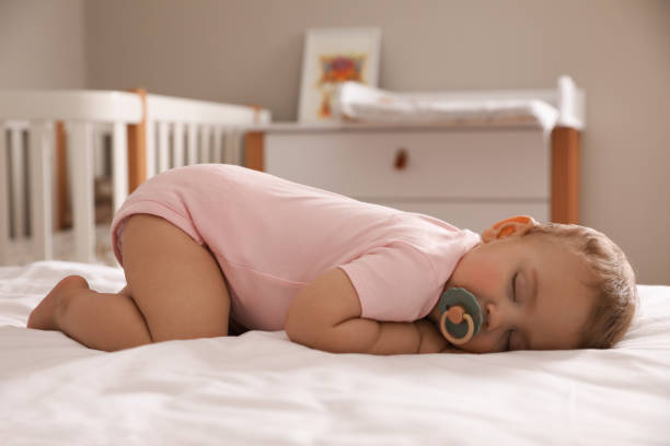 istock Adorable little baby with pacifier sleeping on bed at home 1448786109