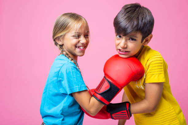Playful caucasian girl and boy boxing with gloves stock photo