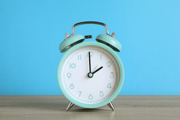 istock Turquoise alarm clock on wooden table against light blue background 1448787052