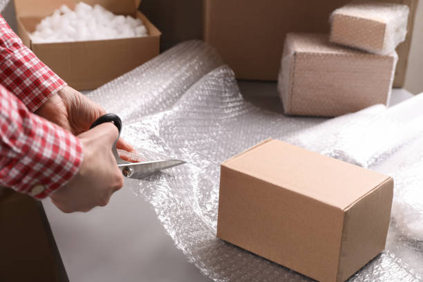 istock Woman cutting bubble pack at table in warehouse, closeup 1448789477