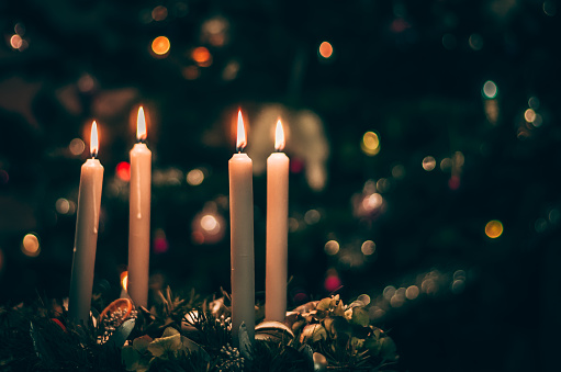 burning candles on advent wreaths with christmas tree background