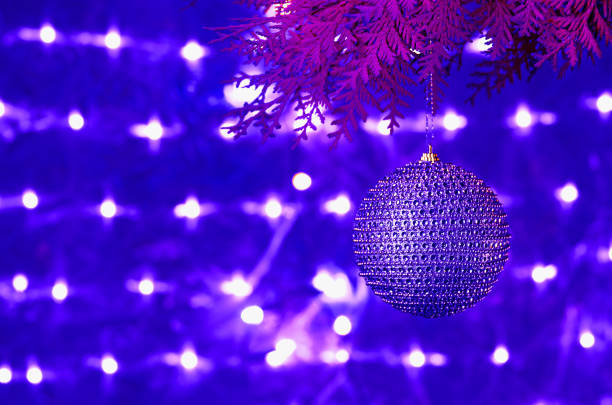 Christmas card, blue shiny ball on a coniferous branch on a blue glowing background.