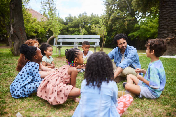 istock Teacher talking with young students on a some grass outdoors 1448790646