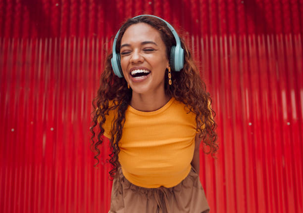 urbain, joie et femme avec musique casque profitant d’un rythme joyeux avec connexion bluetooth. sourire d’une fille latino écoutant pour se sentir bien en streaming audio tout en se reposant au mur pour une pause loisirs. - female likeness audio photos et images de collection