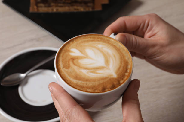 istock Woman with cup of aromatic coffee at table, closeup 1448792614