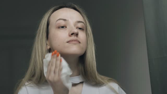 Close-up of a young beautiful woman wipes her face with a wet wipe.