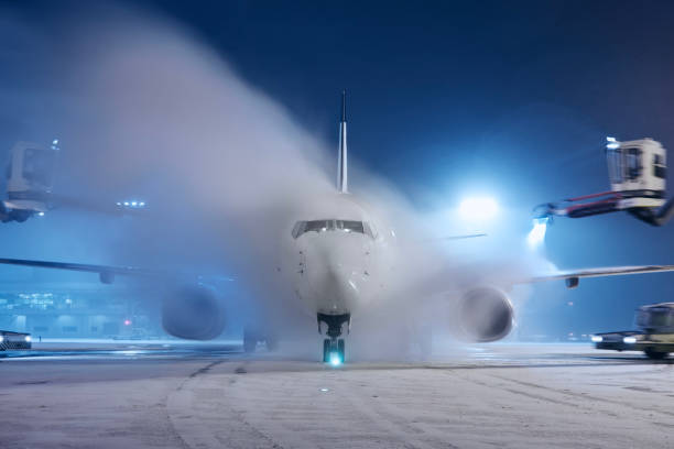Deicing of airplane before flight. Winter night at airport during snowfall.