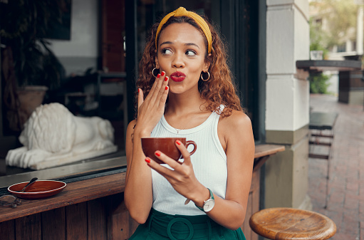 Coffee, cafe and hand of a black woman with manicure nails while sitting by a counter at an outdoor restaurant. Coffee shop, hands and makeup with a young female enjoying a drink from a mug