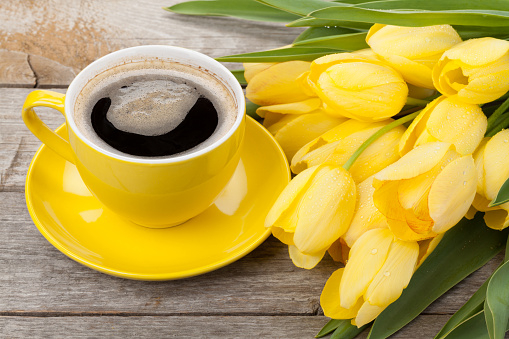 Yellow tulips and coffee cup on wooden table