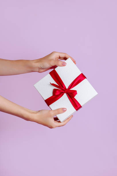 istock Women's hands hold a white with a red ribbon bow 1448803788
