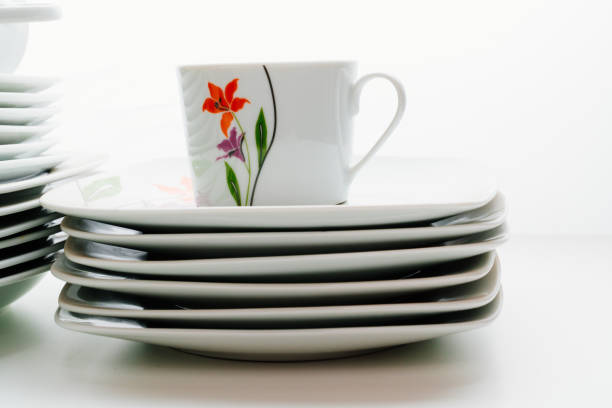A Black Cup of Coffee in a Blue & White Tea Cup with Saucer, an Avocado Green 1960's Vintage Glass Mushroom Paperweight, a Lush Green English Ivy Plant & a Small Rose Plant in Blue & White Pots in Bright Natural Light