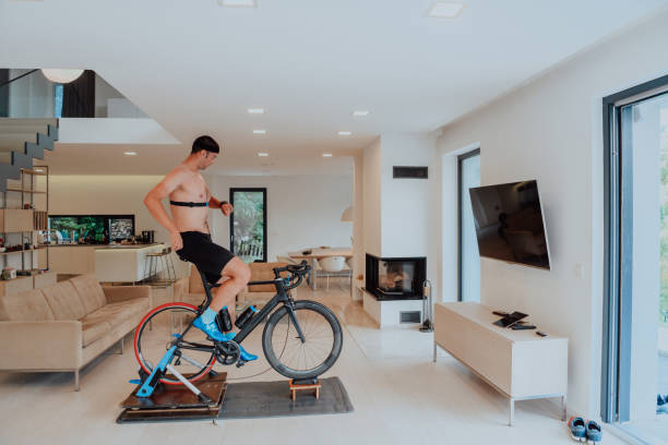 istock A man riding a triathlon bike on a machine simulation in a modern living room. Training during pandemic conditions. 1448808723