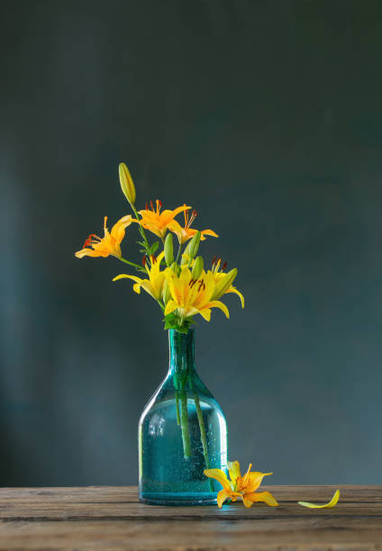 istock yellow lilies in glass vase on dark background 1448810070