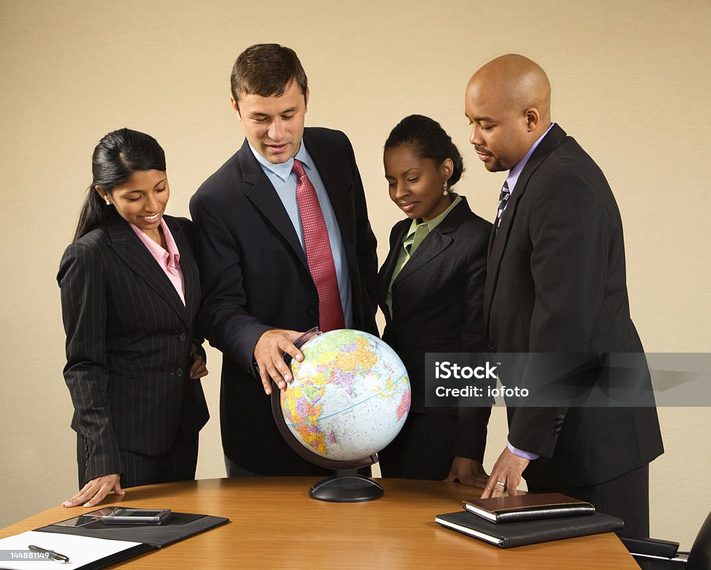 Corporate businesspeople standing around a globe Corporate businesspeople standing around world globe smiling and talking. Outsourcing Stock Photo