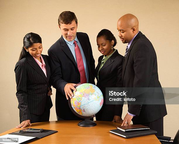 Corporate Businesspeople Standing Around A Globe Stock Photo - Download Image Now - Outsourcing, 25-29 Years, 30-39 Years