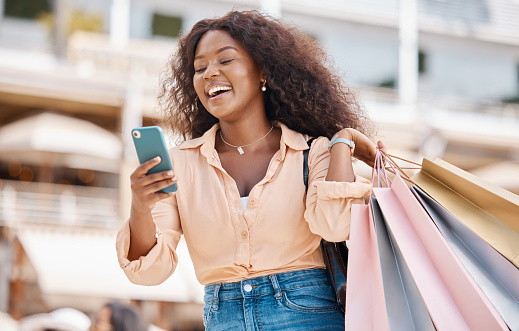 Black woman, shopping bag and city smartphone on social media to search discount codes for fashion sales, online shopping and web connection. Happy street customer using phone on ecommerce mobile app