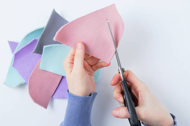 istock Needlework. Caucasian woman cuts pieces fabric with scissors. White background. 1448815730