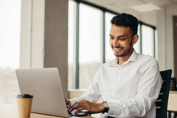 istock Young hindu businessman at workplace with laptop. Office work. 1448817565
