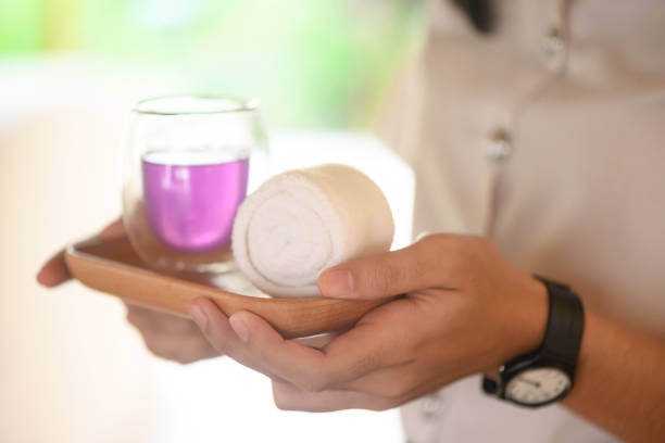 Close-up of employee in spa carrying refreshment tea and warm towel on a service tray, treatment in the spa  center concept
