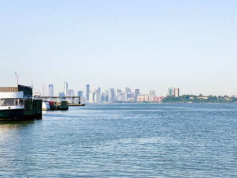 The Jersey City skyline is reflected in the Hudson River as seen from Manhattan, New York at dawn.