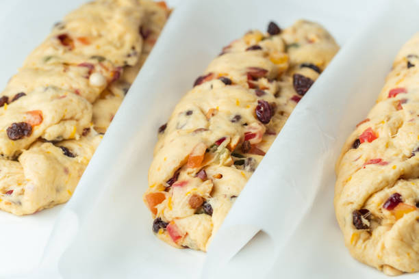 Traditional Christmas Stollen pie is ready for baking in the oven. Making German Christmas bread with raisins and candied fruits . White background. Template for a Christmas pastry recipe