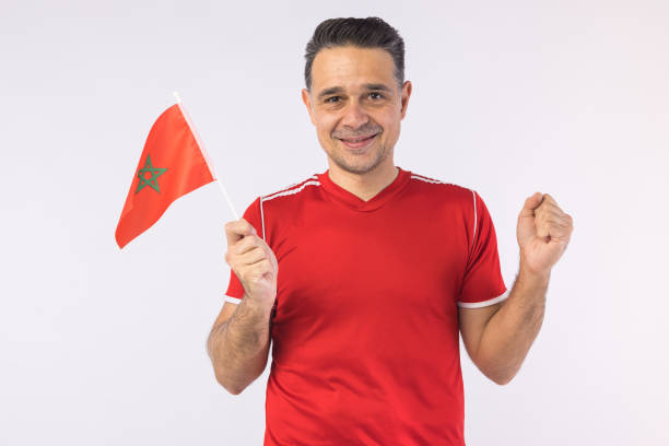Man wearing a red shirt, holding a Moroccan flag. Sport, world cup and fan concept. stock photo