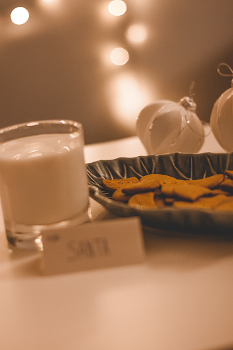 Christmas greeting card with gingerbread in a bowl with a glass of milk next to it, Christmas bokeh lights in the background