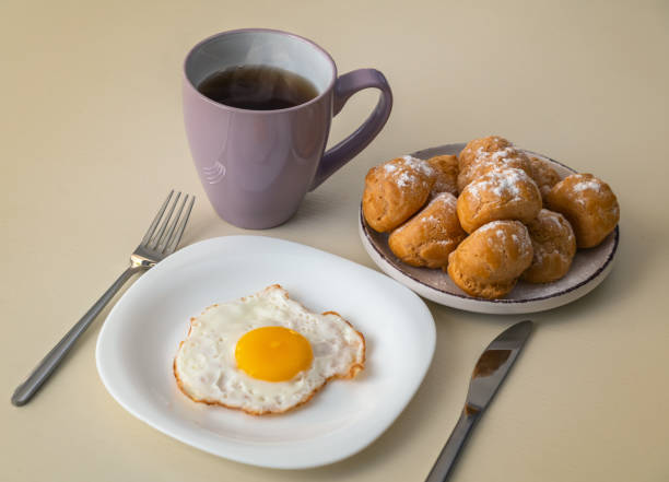 istock Breakfast with fried eggs, a cup of tea and profiteroles 1448833809