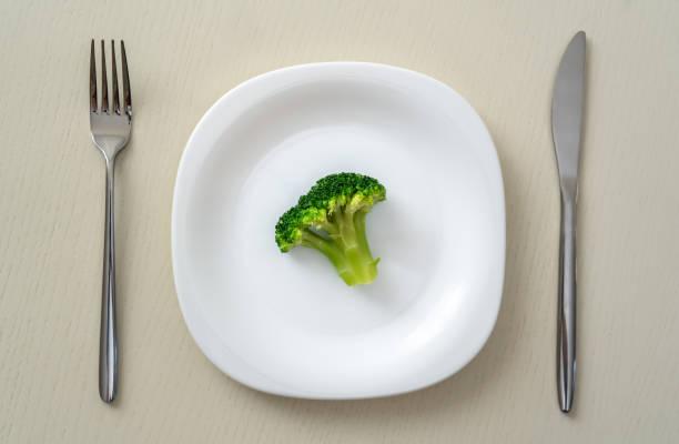 istock A small portion of boiled broccoli on a white plate with a knife and fork, minimum calories 1448833855