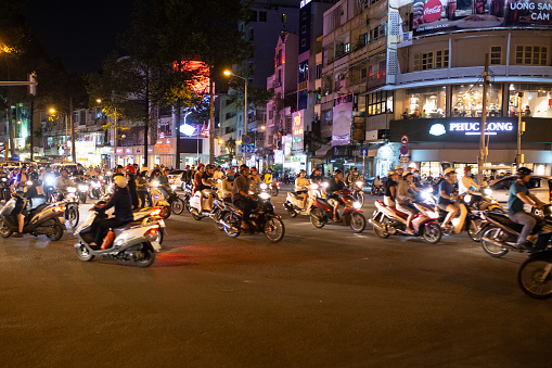 The chaos of an intersection in the center of Ho Chi Minh City, on a hot evening just after dark. The busy capital in southern Vietnam