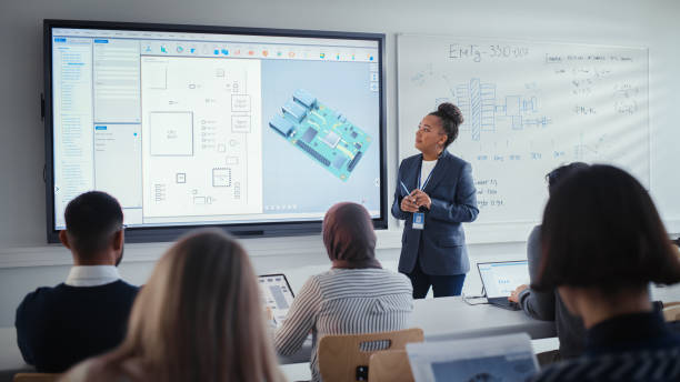 istock Diverse Team of Computer Engineering Students Listening to Black Teacher on Seminar, Watching Interactive Whiteboard With 3D Model of Processor. Innovative Techniques in Technology Concept. 1448836856