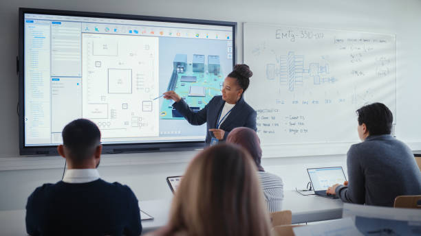 istock Diverse Team of Computer Design Students Listening to Black Teacher on Seminar, Watching Interactive Whiteboard With 3D Model of Processor. Innovative Techniques in Technology Concept. 1448836902