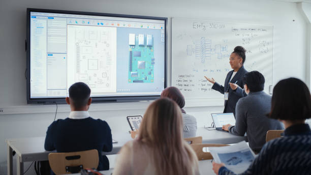 istock Black Female Teacher Using Digital Interactive Screen, Talks to Group of Diverse Students and Shows 3D Circuit Board Components. Education and University of Technology Concept. 1448836928