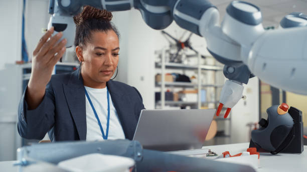 istock Portrait of Black Female Senior Engineer Working on Engineering Project, Coding on Laptop and Changing Robotic Hand Position in Modern Office. Empowered Scientist with Creative Project. 1448837333