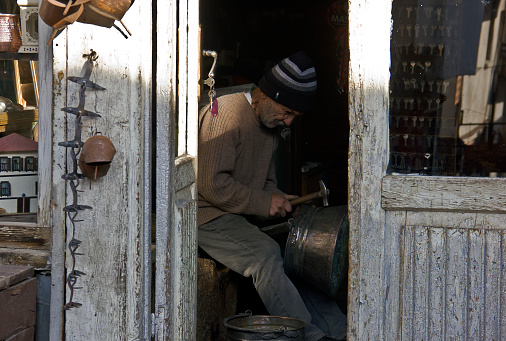 Bolu, Turkey - November 28, 2022: Tinner people with tinsmith craft product view in mudurnu. Residents are on the streets near traditional and historical Anatolian houses view with old bazaar. Houses built by ottomans in 19th century in Mudurnu which is located eastern bolu city, turkey.