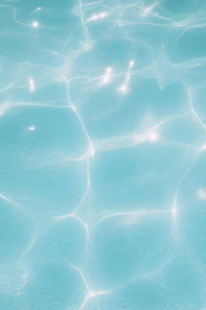 Background, blue water waves in the pool with sun reflection. Selective focus stock photo