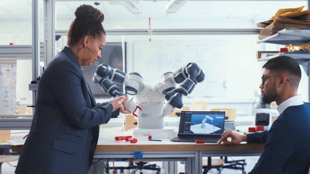 istock Chief Engineer and Young Computer Science Specialist with Laptop Analyse and Discuss How Futuristic Robotic Arm Works. Promising and Smart Engineering Majors Collaboration Concept. 1448840133