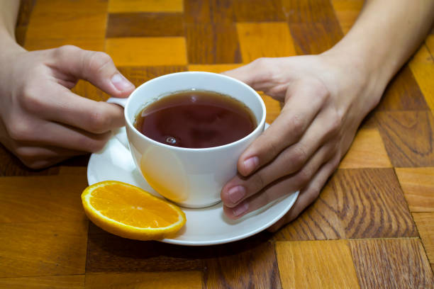 A white cup of tea in his hands on a wooden table. High quality photo