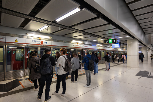 Hong Kong - December 13, 2022 : Passengers at the MTR Austin Station in Kowloon, Hong Kong. It is an underground MTR station on the Tuen Ma line in Hong Kong.