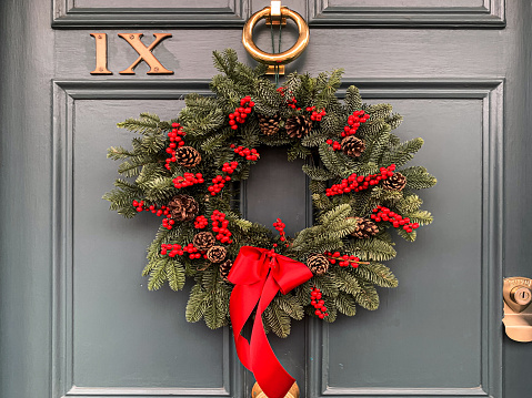 Christmas mood: festive christmasy themed winter natural wreath on a grey wooden door. Charming wreath. Christmas decoration
