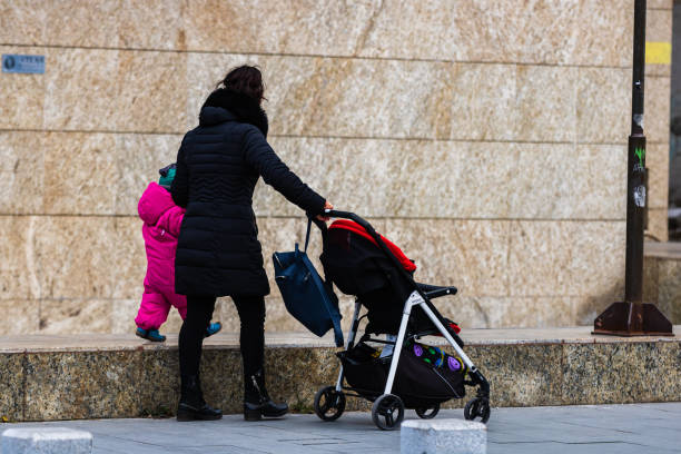 Single mom with child pushing baby stroller in Bucharest, Romania, 2022