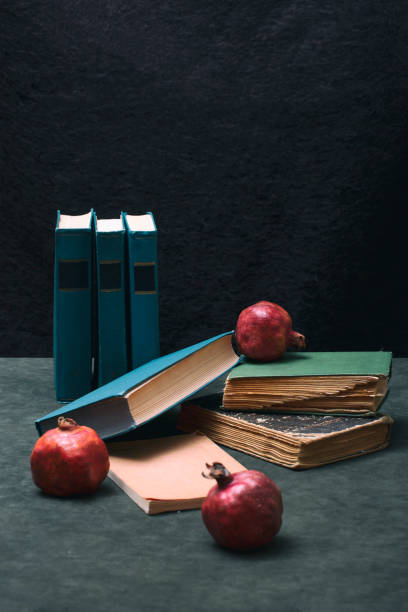 istock Ripe red pomegranates with books on the table 1448859769