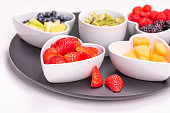 Assorted fresh berries and fruits in heart bowls on white background, copy space