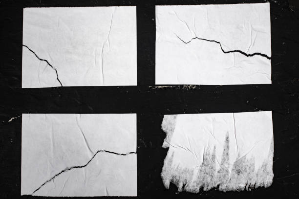 istock Four torn sheets of white paper on a black wall. 1448864826