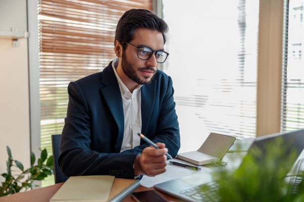 istock Focused indian businessman in suit working with documents from home office 1448864949