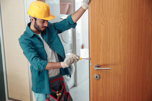 istock Locksmith workman in uniform installing door knob. Professional repair service 1448865938
