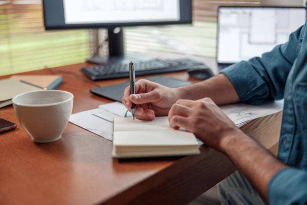 istock Close up of man hands making notes in notepad while sitting on his workplace 1448866140