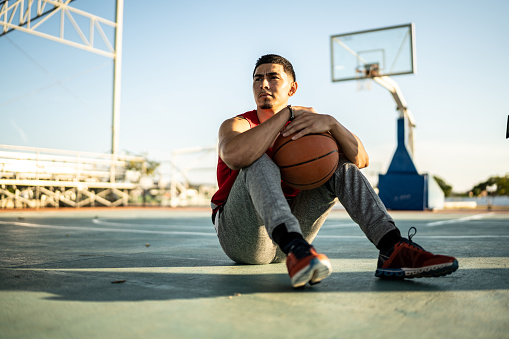 Basketball player sitting on the sports court
