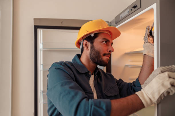 istock Male technician in uniform with screwdriver repairing refrigerator in kitchen 1448866262