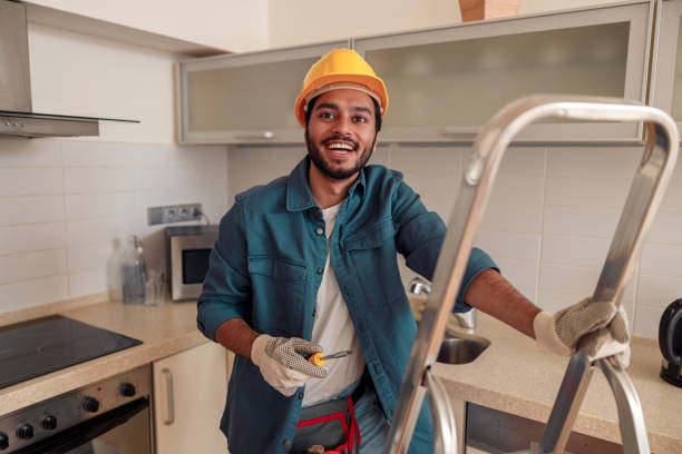 smiling handyman is standing on ladder in kitchen and holding a screwdriver - ladder company 1 imagens e fotografias de stock